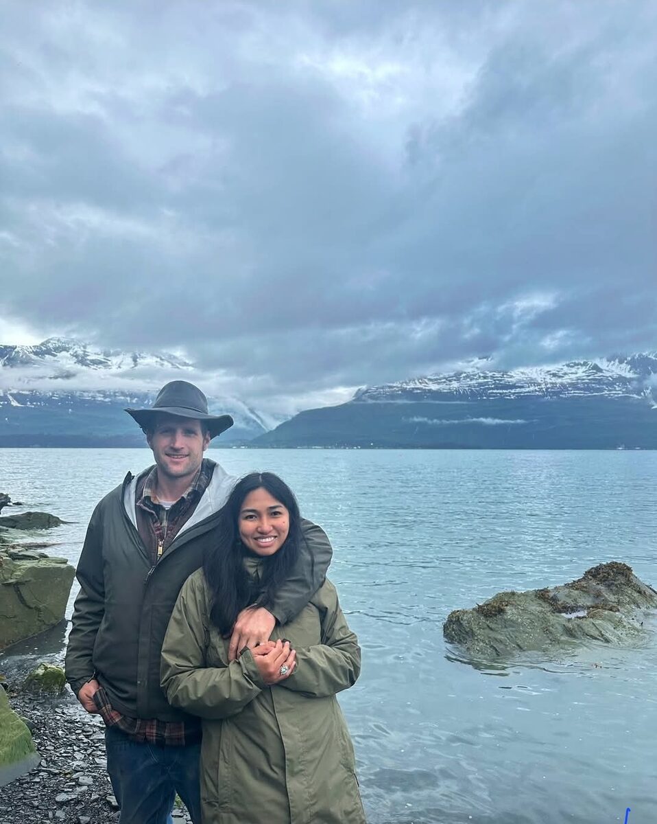 The family, husband and wife, in front of Alaska mountains and water
